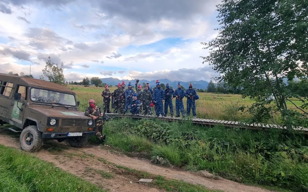 Grupa graczy paintballowych i terenowy samochód wojskowy na tle Tatr